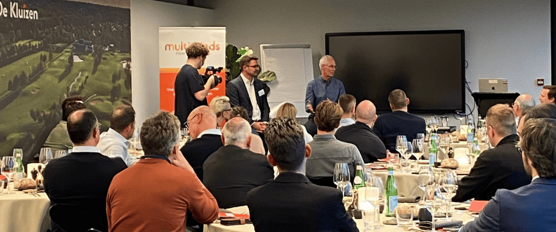 Audience attending a business presentation, with two speakers and a videographer at the front.