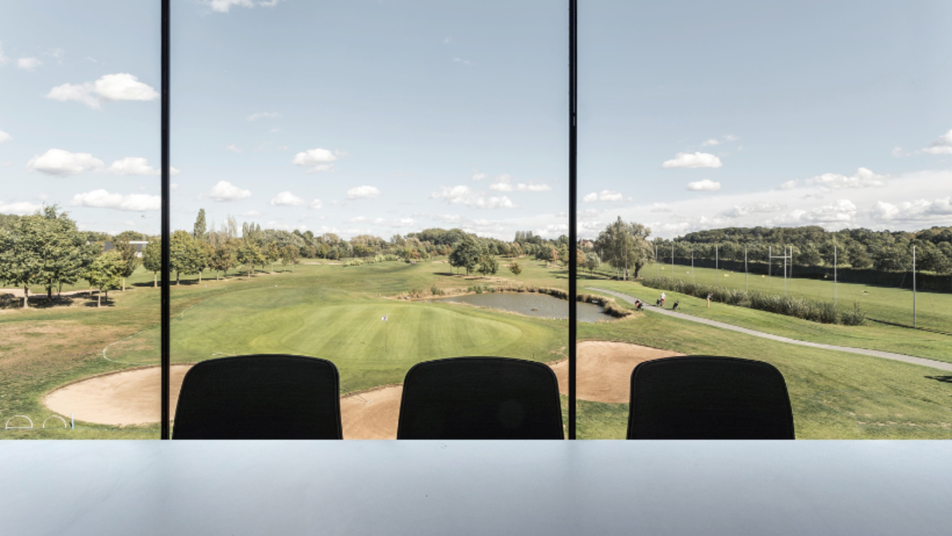 Golf course view from a window with green grass, trees, and small pond.