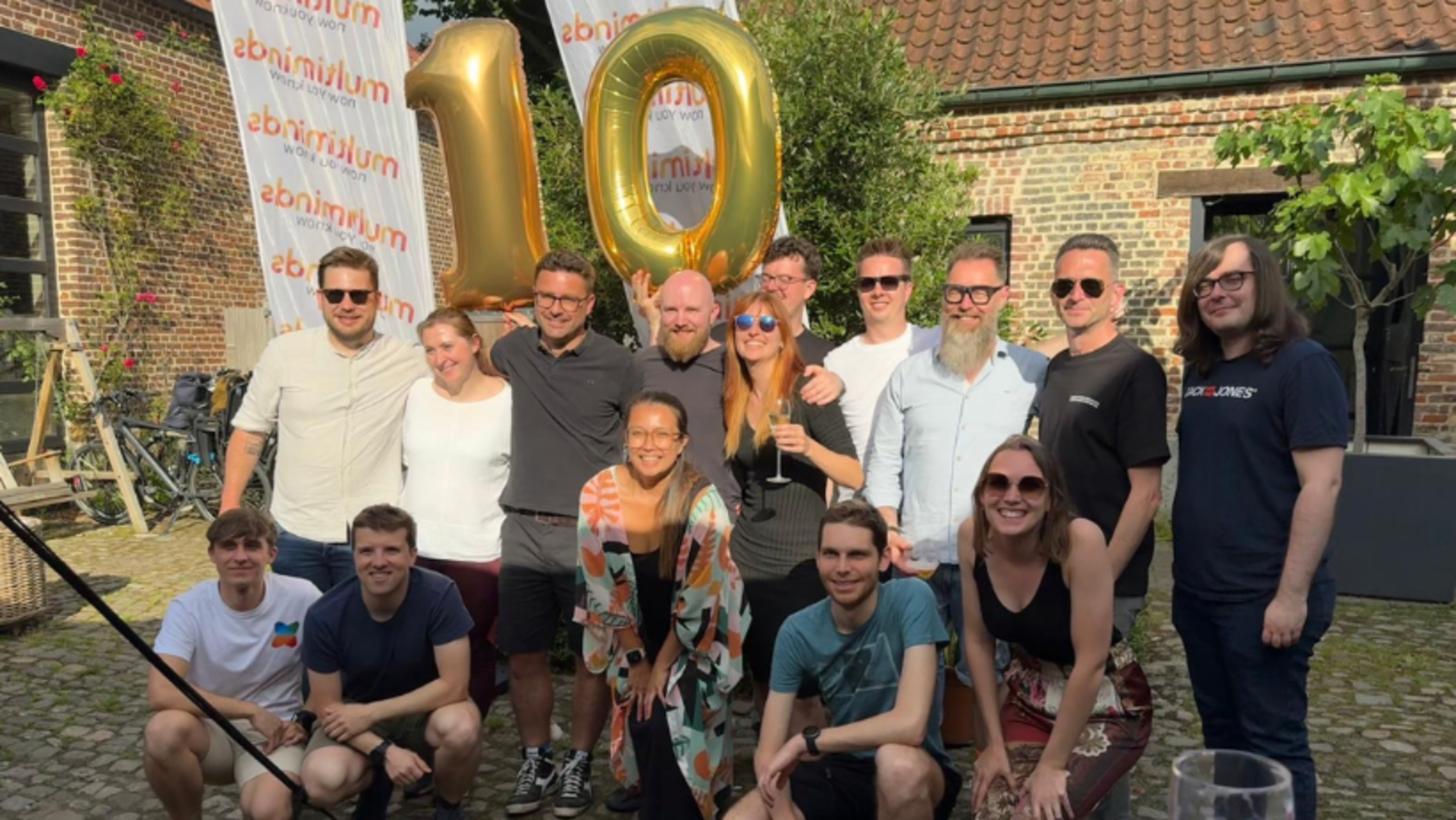 Team celebrating 10 years with gold balloons outdoors.