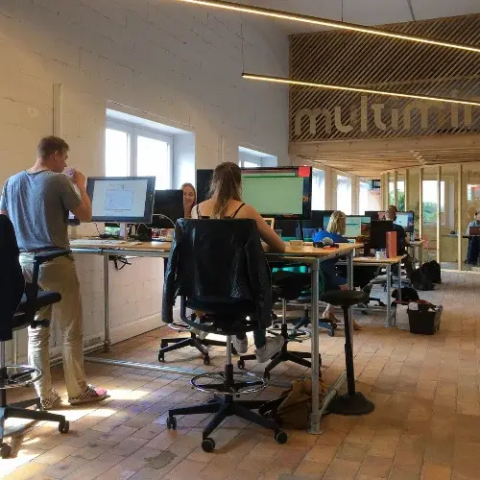 People working at computer desks in a modern open-plan office space.