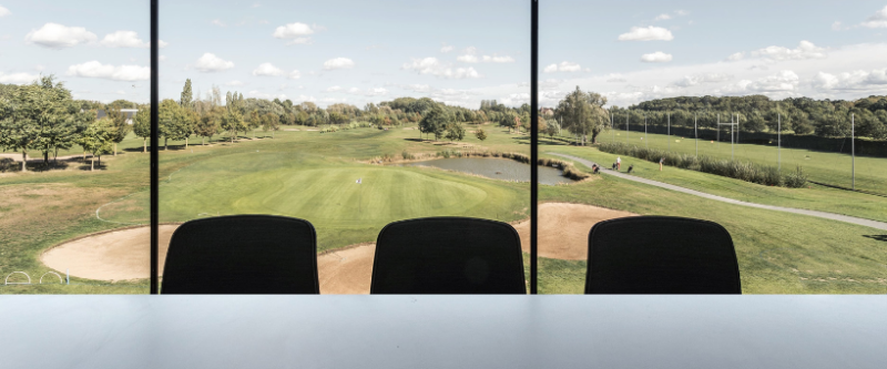Golf course view from a window with green grass, trees, and small pond.