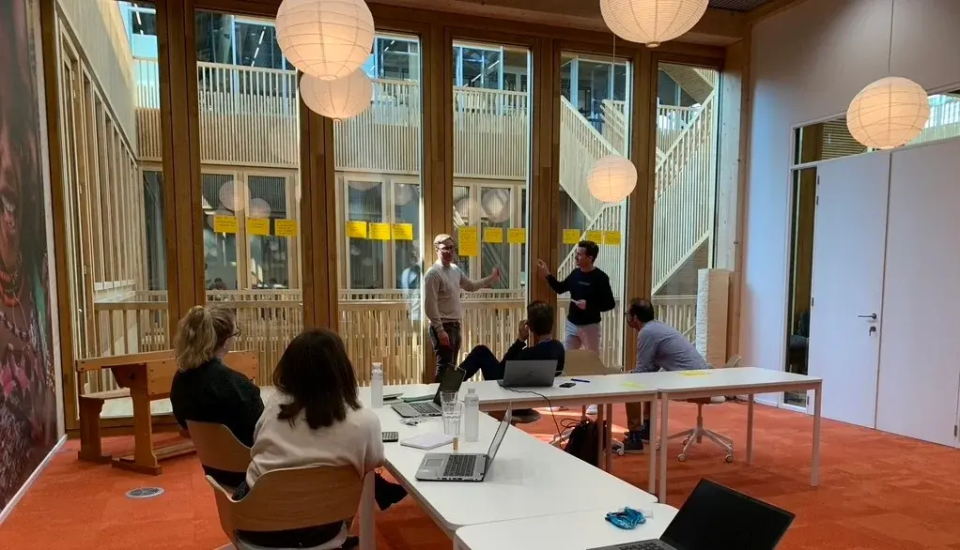 Colleagues collaborating during a brainstorming workshop in a modern office with sticky notes on glass walls.
